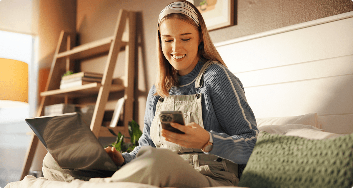 Woman on phone and laptop smiling